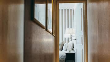 A hallway leading to a bedroom with a bed, a nightstand, and a lamp.