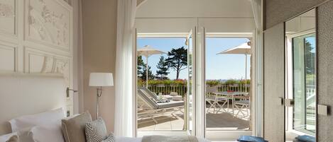Habitación de hotel con una cama grande, un balcón con mobiliario exterior y vistas al exterior.