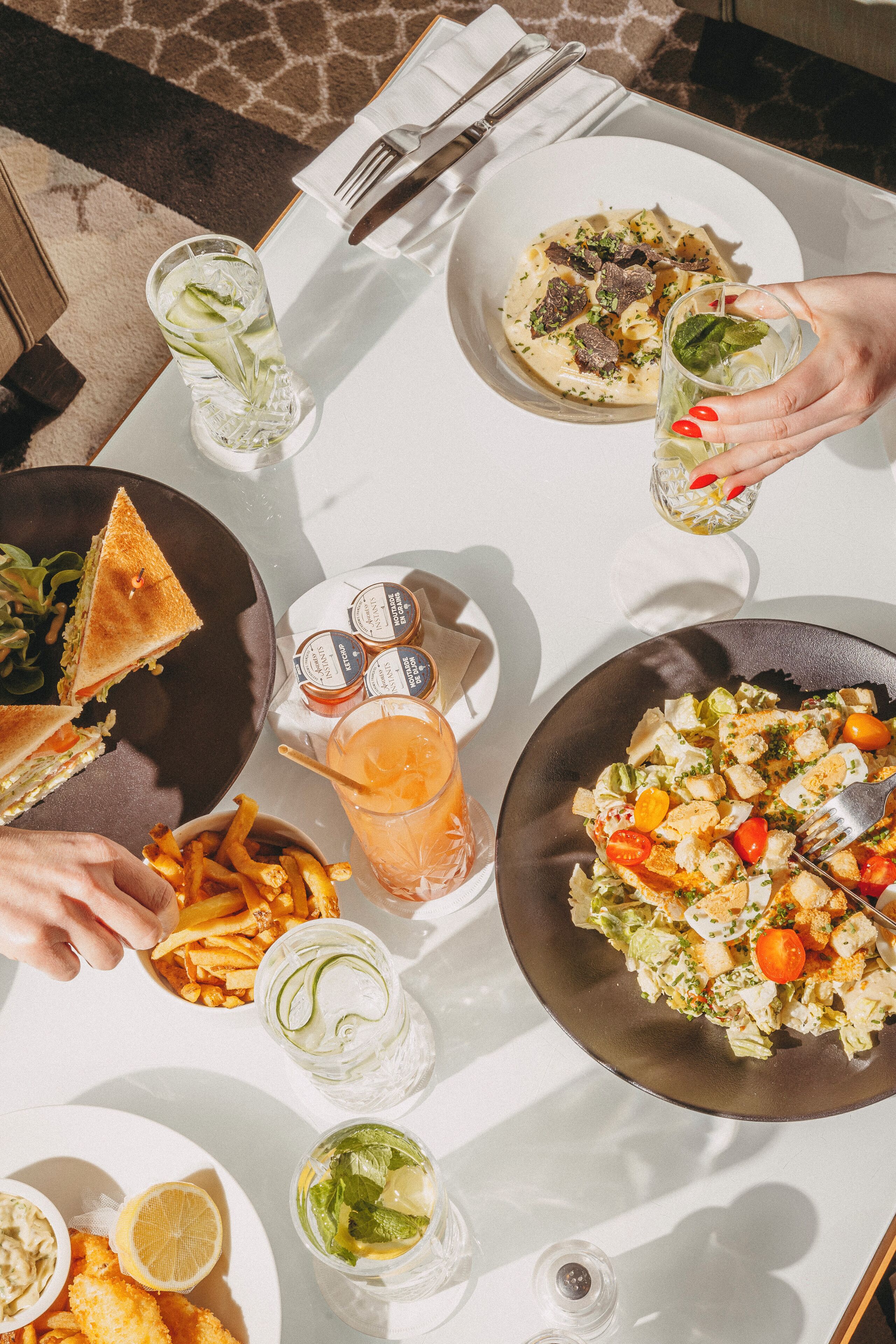 Una mesa dispuesta con diferentes platos, bebidas y cubiertos, mostrando una preparación para comer.