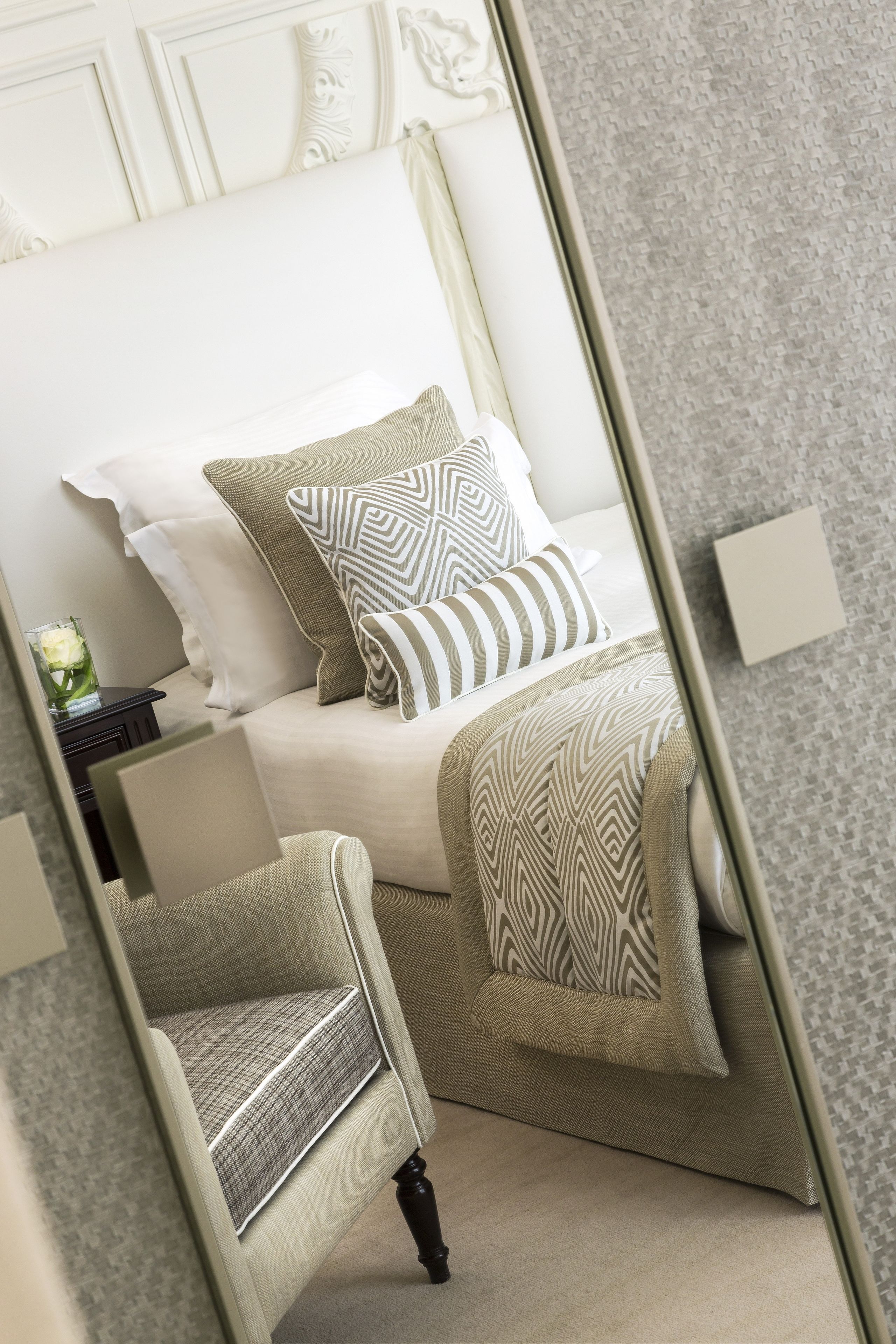 A bedroom with a bed, pillows, a chair, and a nightstand.