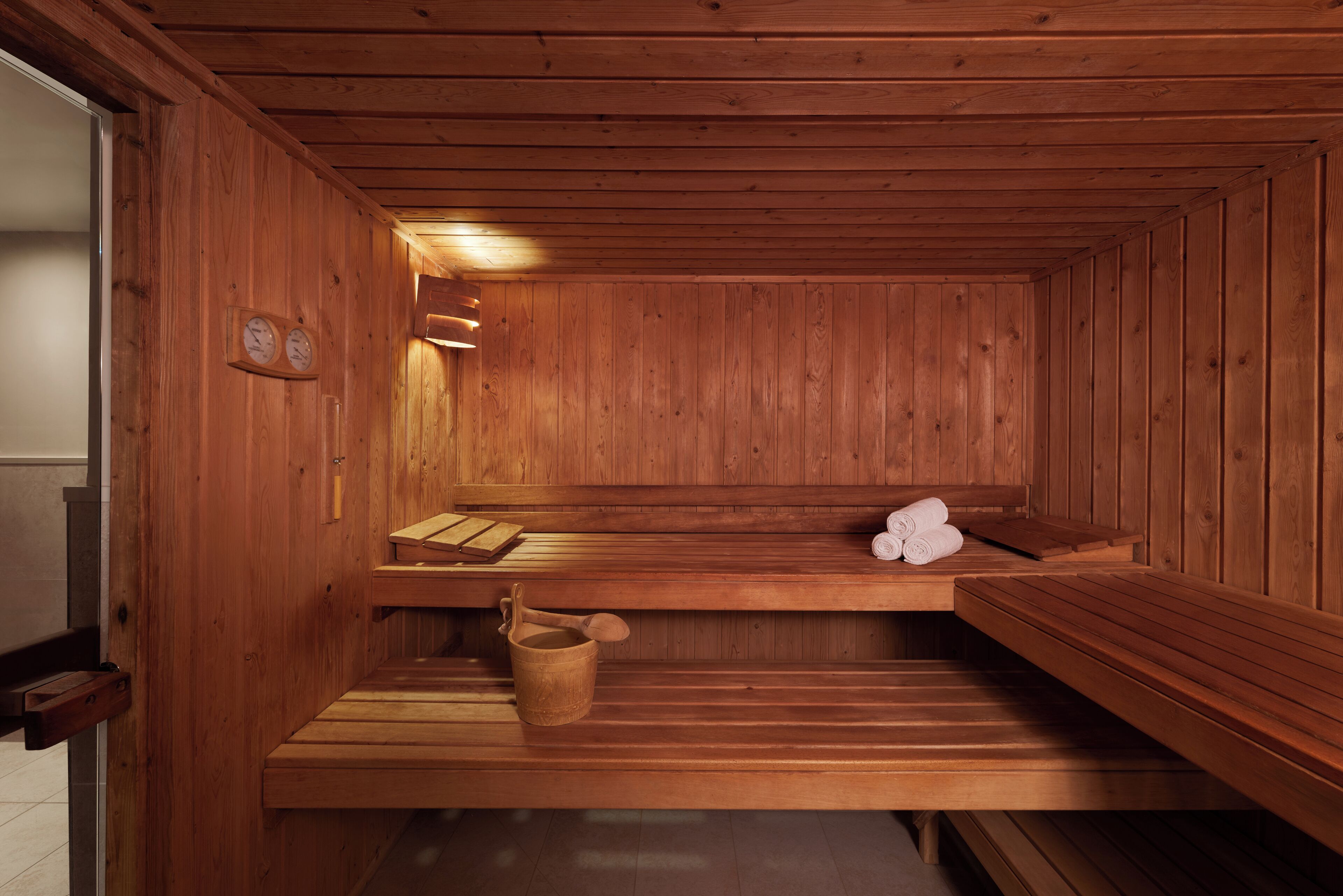A wooden sauna with benches and a wooden bucket.