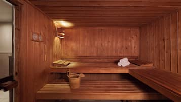 A wooden sauna with benches and a wooden bucket.