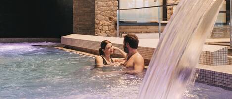 Een koppel in een jacuzzi met een waterval.