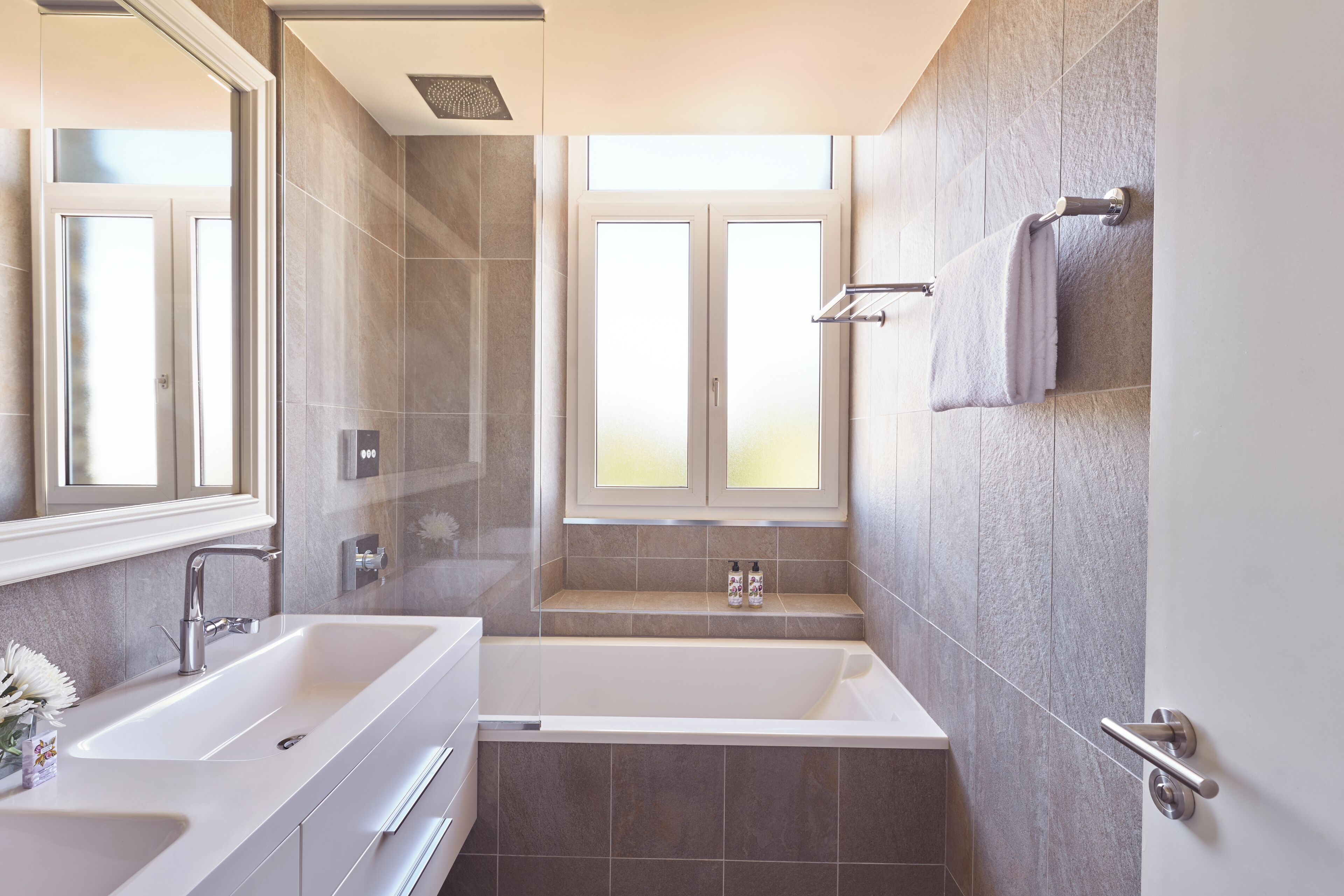 Un baño moderno con una bañera grande, lavamanos doble y un ventanal que proporciona luz natural.