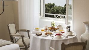Una mesa de desayuno con diferentes alimentos y vista al mar a través de una ventana.