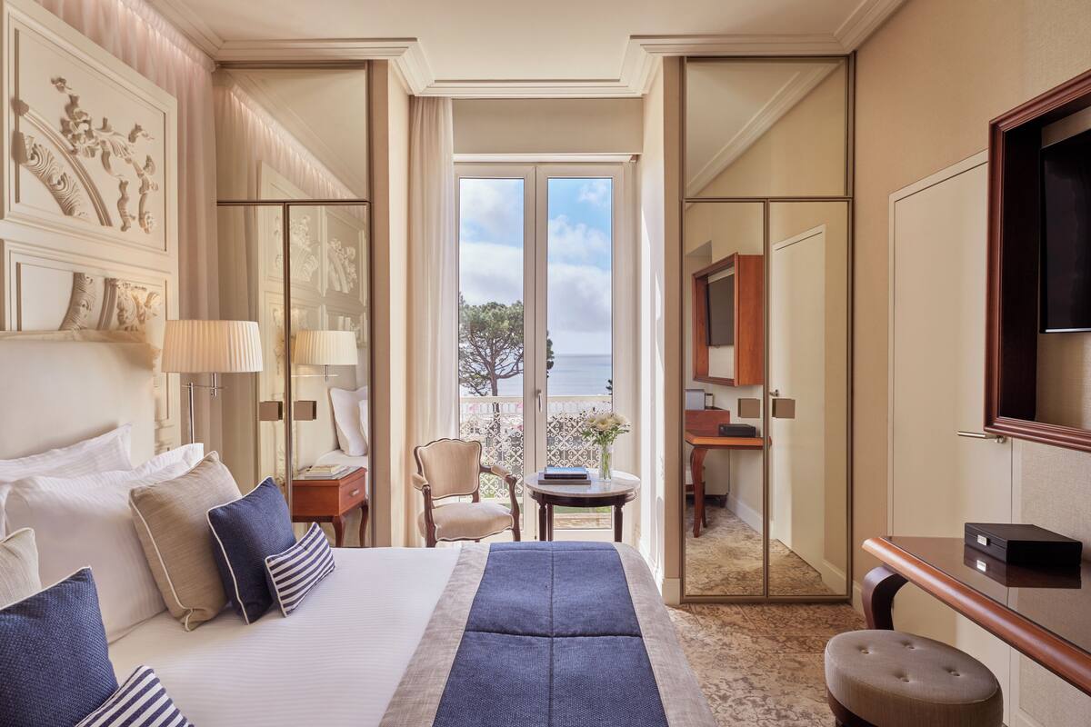 Quarto de hotel com uma cama grande, uma escrivaninha, uma cadeira e vista para o exterior.
