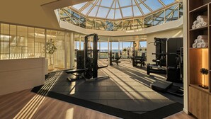 Un gimnasio con equipo de ejercicio, tragaluces y vistas al exterior.