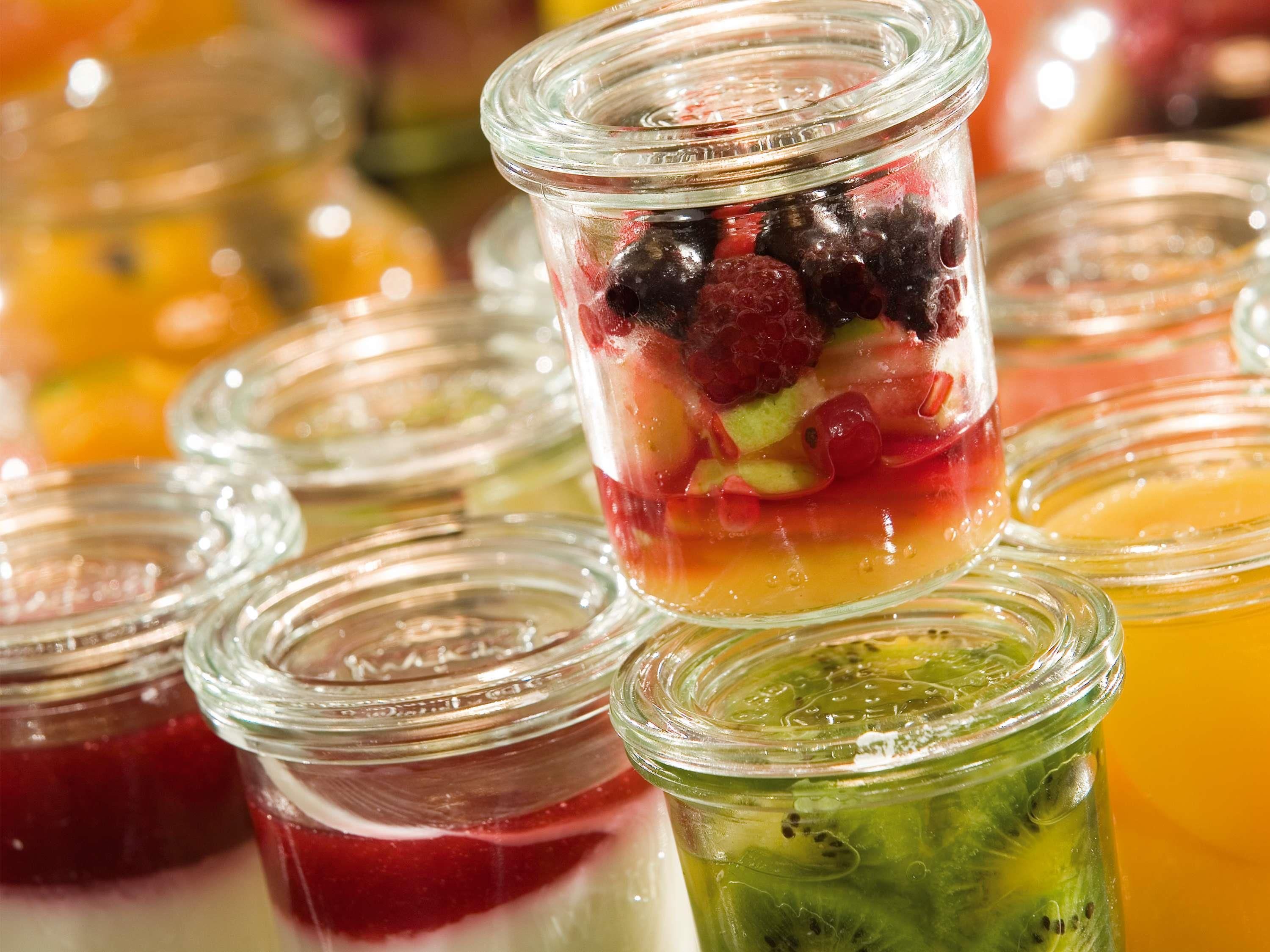 A variety of fruit-based desserts in clear glass jars.