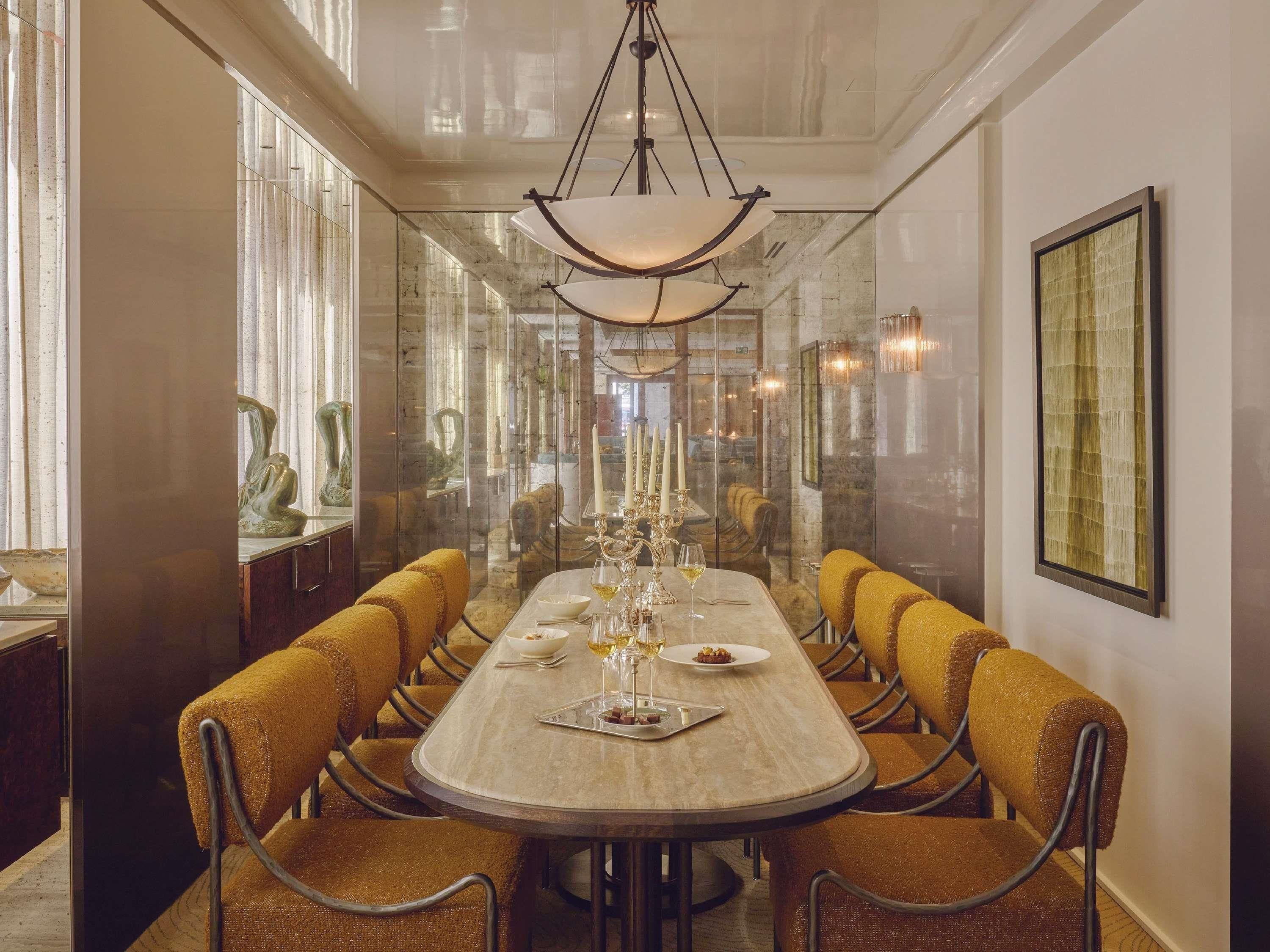 A dining area with a long table, chairs, and a chandelier.