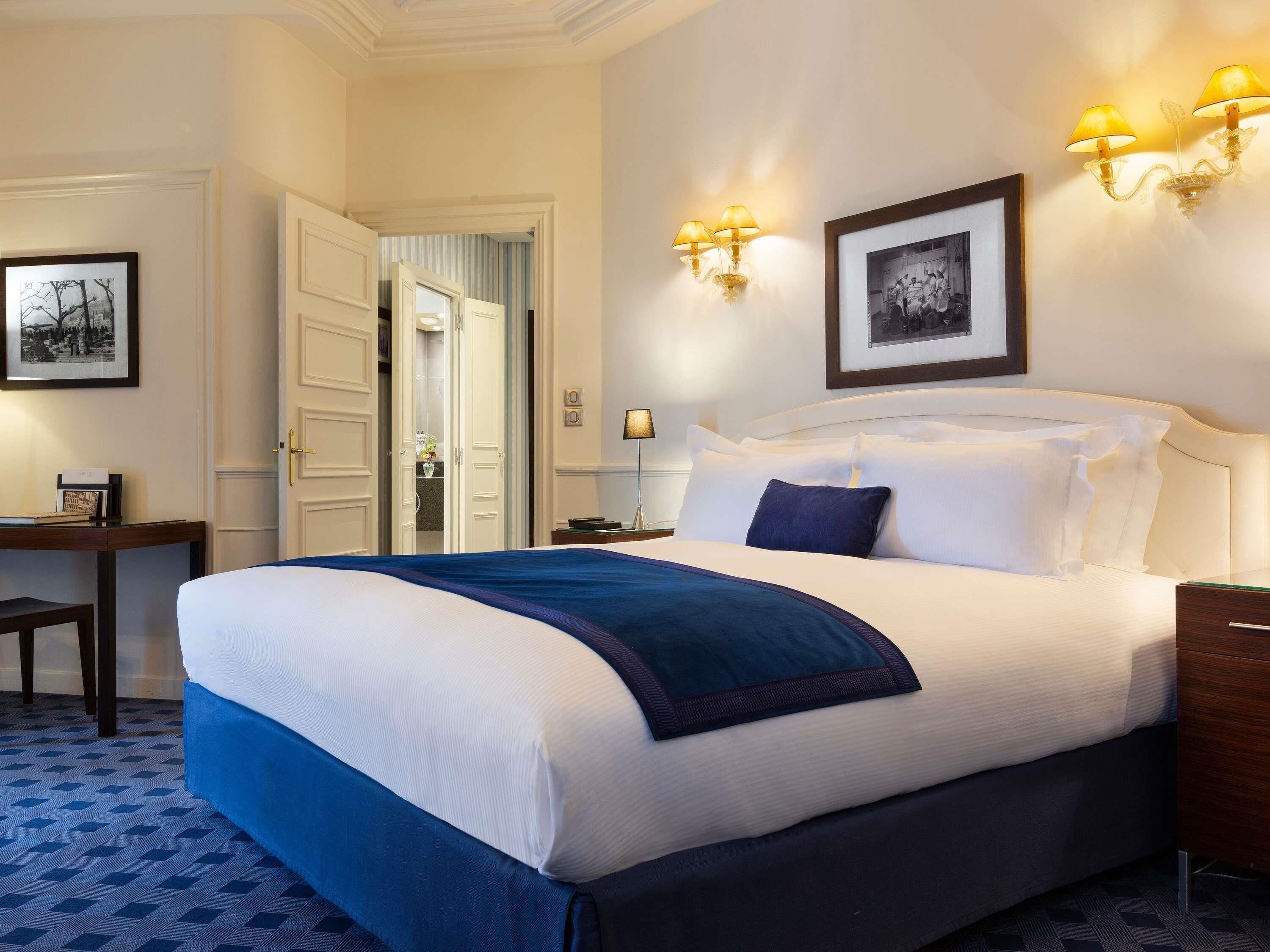 Een hotelkamer met een groot bed, een bureau, een stoel en twee wandlampen.
