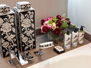 A bathroom vanity with black and white patterned boxes, a vase of flowers, and toiletries. - Le Royal Hotel Lyon - MGallery Collection (Lyon)