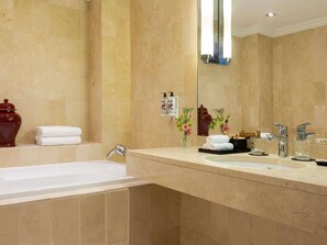 A bathroom with a bathtub, a large mirror, and a vanity with a sink and two faucets. - Le Royal Hotel Lyon - MGallery Collection (Lyon)
