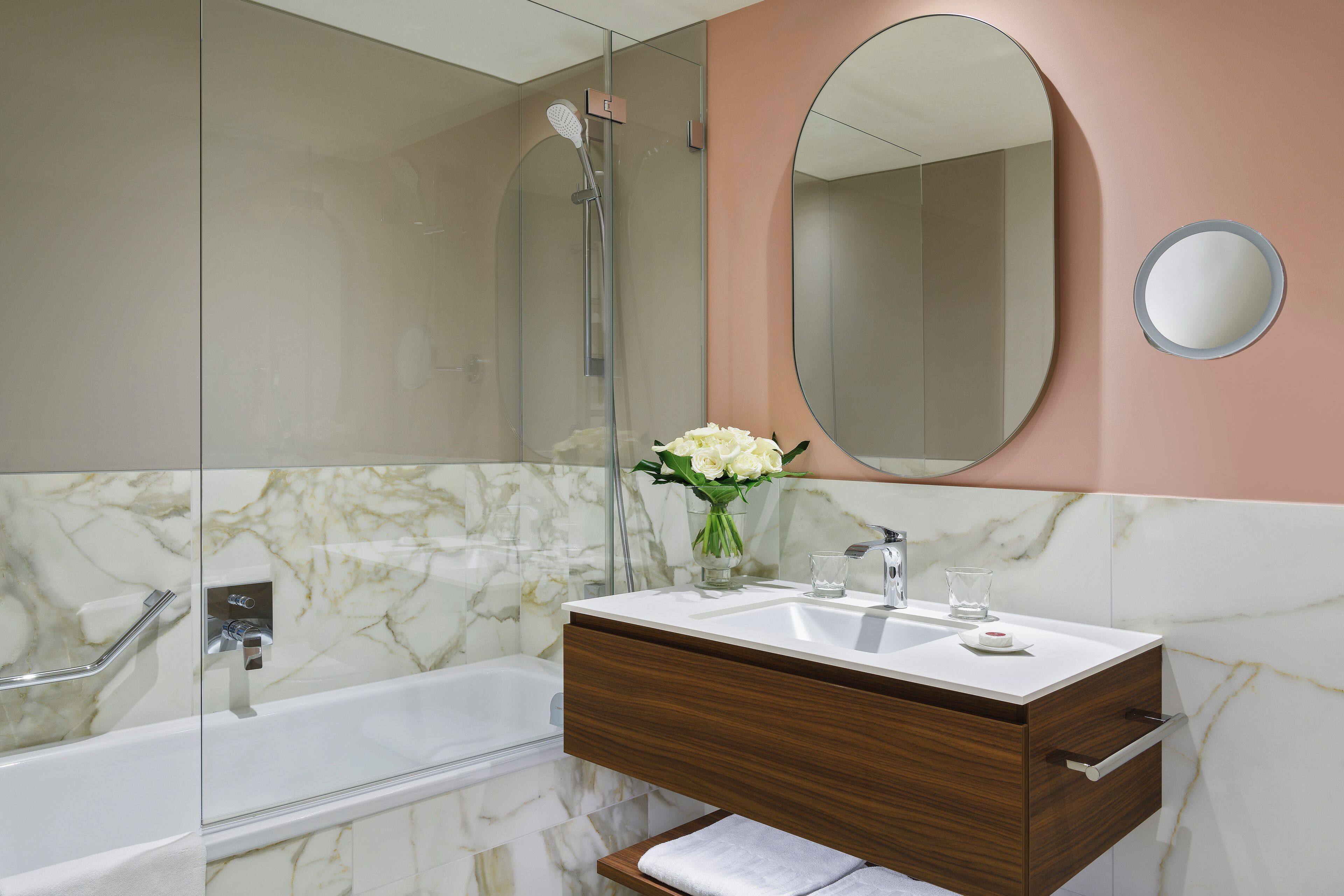 Une salle de bain avec un meuble-lavabo en marbre, une baignoire, une douche et un grand miroir.