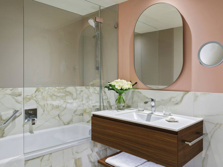Une salle de bain avec un meuble-lavabo en marbre, une baignoire, une douche et un grand miroir.