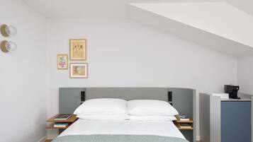 Een moderne slaapkamer met een bed, nachtkastjes, een bureau en afbeeldingen in lijsten aan de muur.