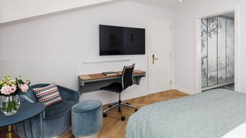 Ein modernes Schlafzimmer mit Bett, Schreibtisch, Stuhl, Fernseher und einer dekorativen Wandverkleidung.