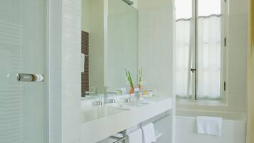 A modern bathroom with a large mirror, two sinks, a shower, and a toilet.