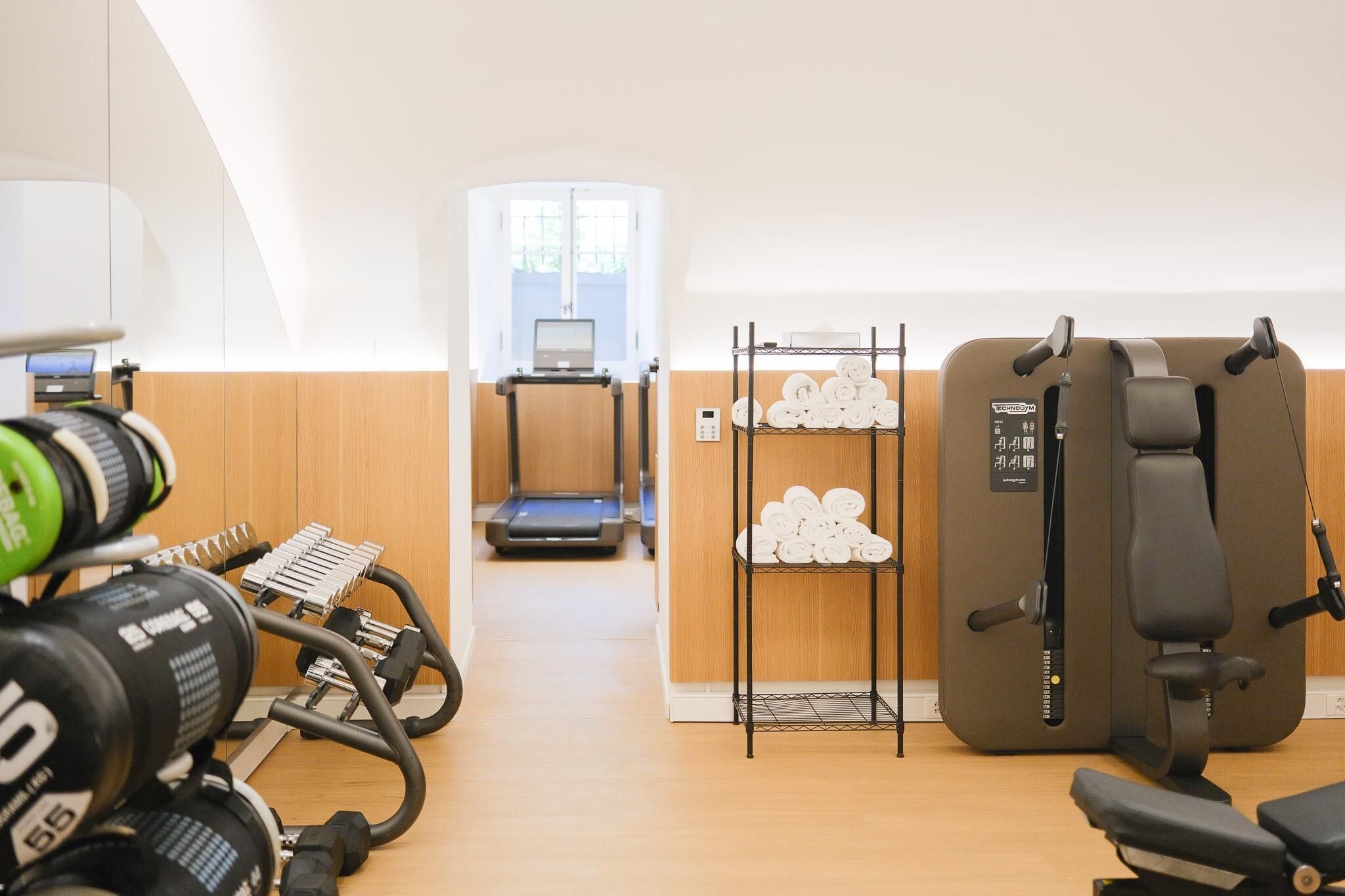 A gym with exercise equipment, a treadmill, and a wall-mounted rack with towels.