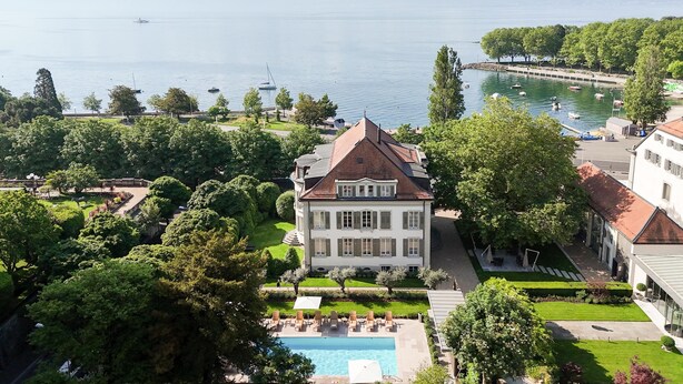 Un grand bâtiment doté d’une piscine, entouré d’arbres et offrant une vue sur l’eau.