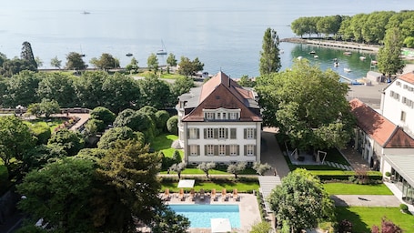 Un grande edificio con piscina, circondato da alberi e vista sull'acqua.. Hotel Angleterre
