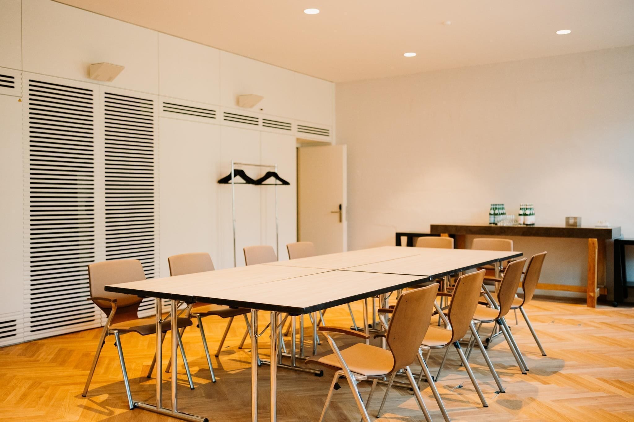 Una sala conferenze con un lungo tavolo, sedie e un angolo cottura.