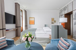 Una habitación de hotel moderna con cama, televisor, escritorio y sofá azul.