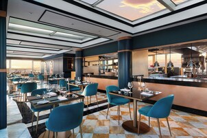 Un ristorante moderno con soffitto alto, ampie finestre e pavimento a scacchi.
