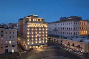 Un hotel a più piani con un evidente cartello "BERNINI", caratterizzato da una fila di finestre uniformemente illuminate e un ingresso centrale.