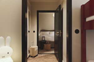 A hotel room with a bed, a suitcase, a handbag, and a white rabbit decoration.