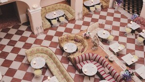 A checkered floor with various seating areas, including sofas and round tables, arranged in a spacious indoor setting. - Hotel Bella Grande (Copenhagen)