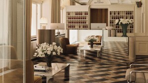 A hotel lobby with a checkered floor, seating areas, a reception desk, and a wine display. - Hotel Bella Grande (Copenhagen)