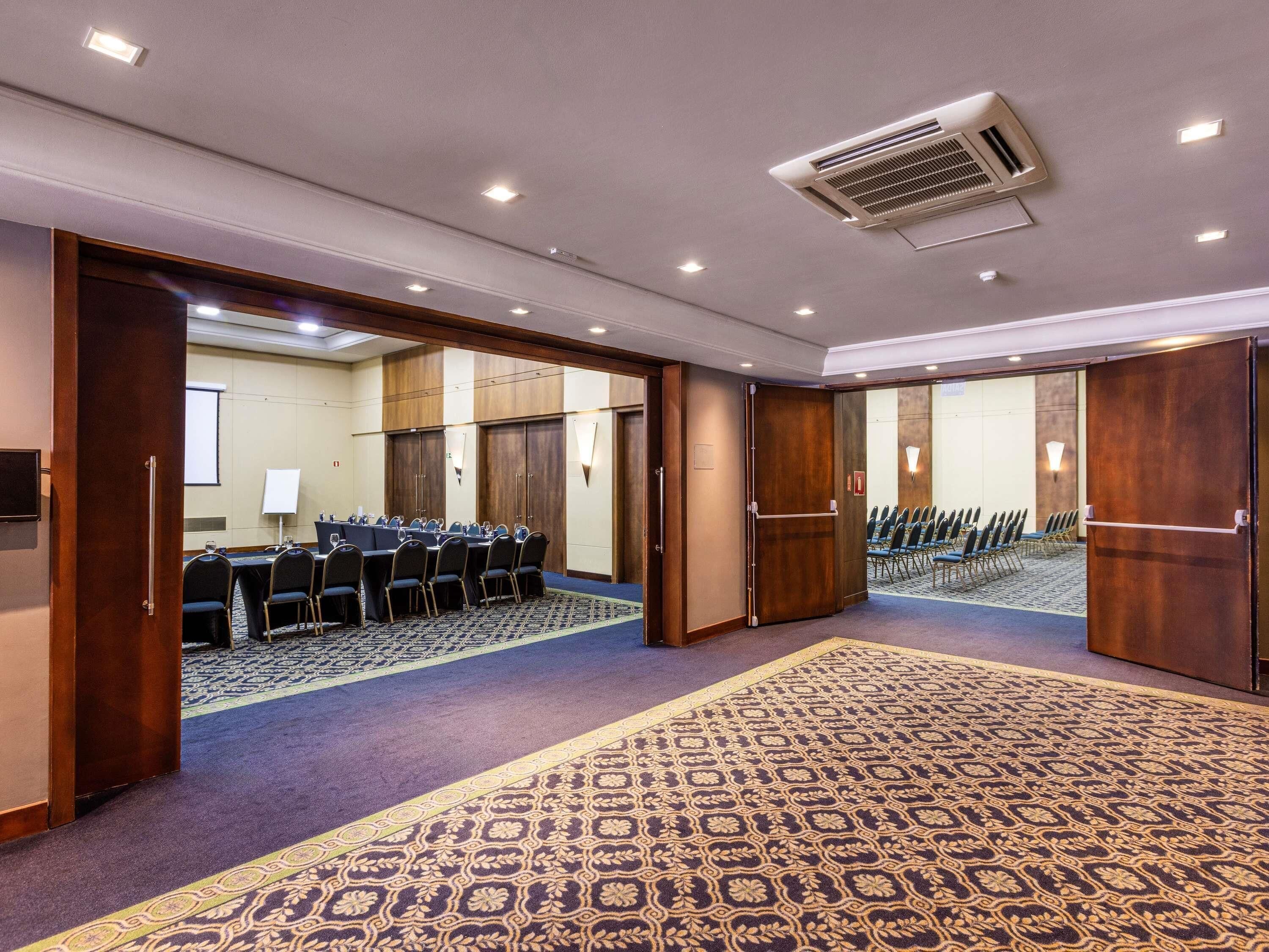 A conference room with a long table, chairs, and a carpeted floor.