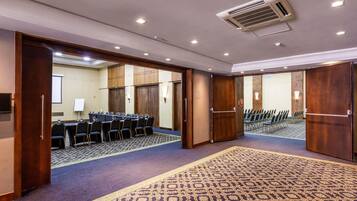 A conference room with a long table, chairs, and a carpeted floor.
