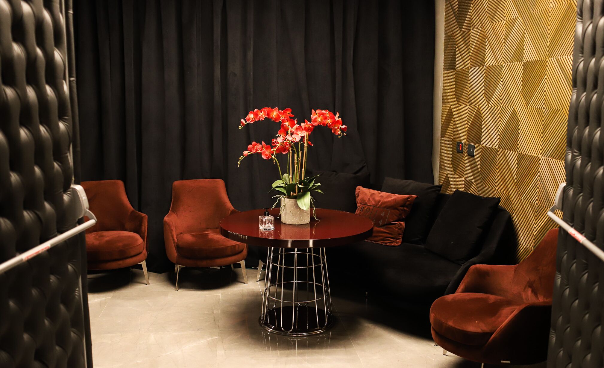 Un área de estar moderna con una mesa redonda, sillas rojas y un sofá negro.