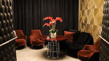 Un área de estar moderna con una mesa redonda, sillas rojas y un sofá negro.