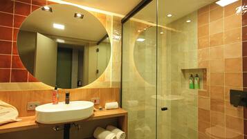 Un baño moderno con un espejo redondo, un lavabo y una cabina de ducha de vidrio.