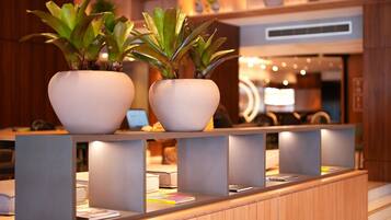 Una mesa de recepción con dos plantas en macetas, un mostrador de madera y una decoración interior moderna.