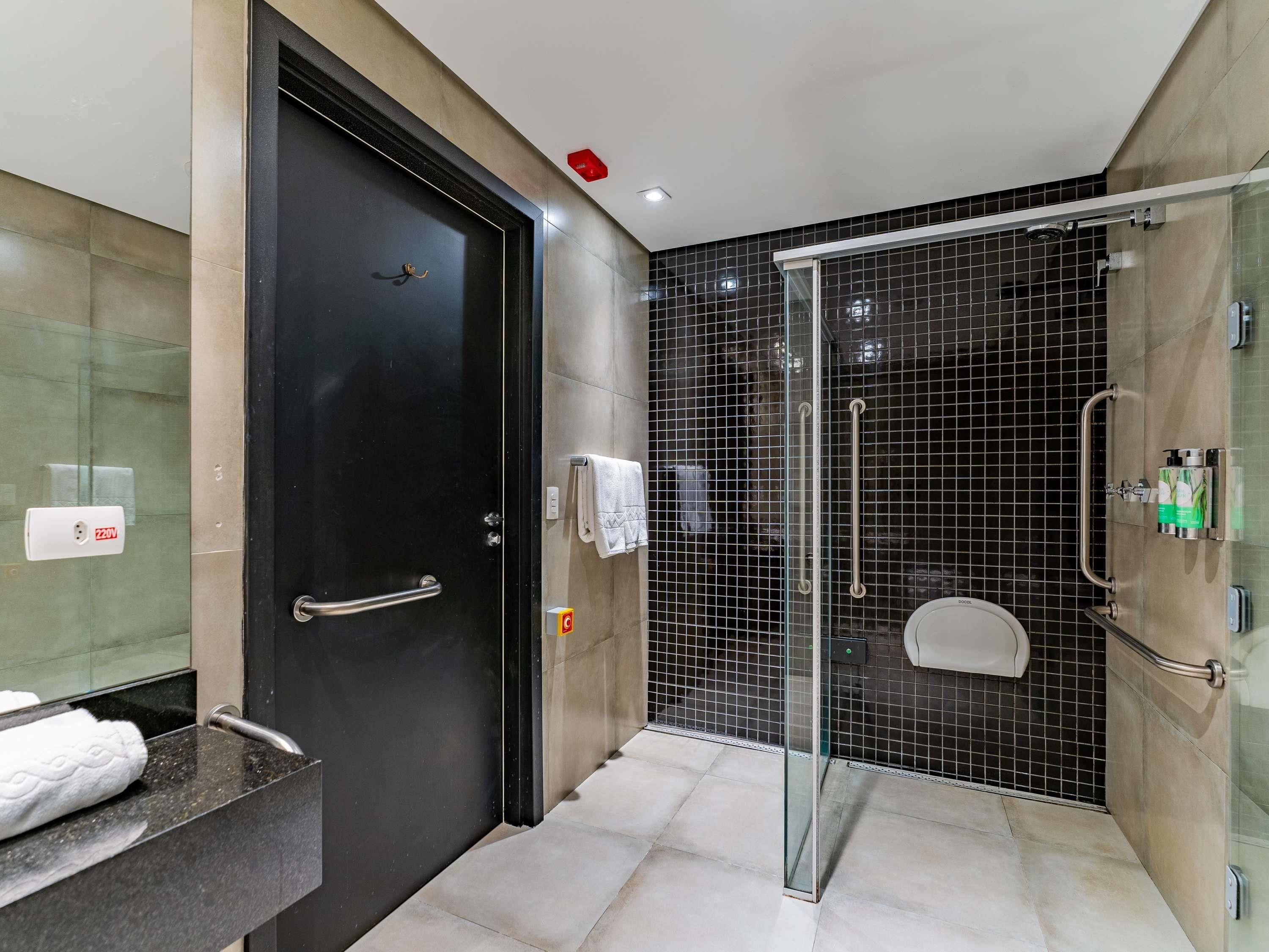 Casa de banho moderna com cabine de duche em vidro, porta preta e toucador com toalha.