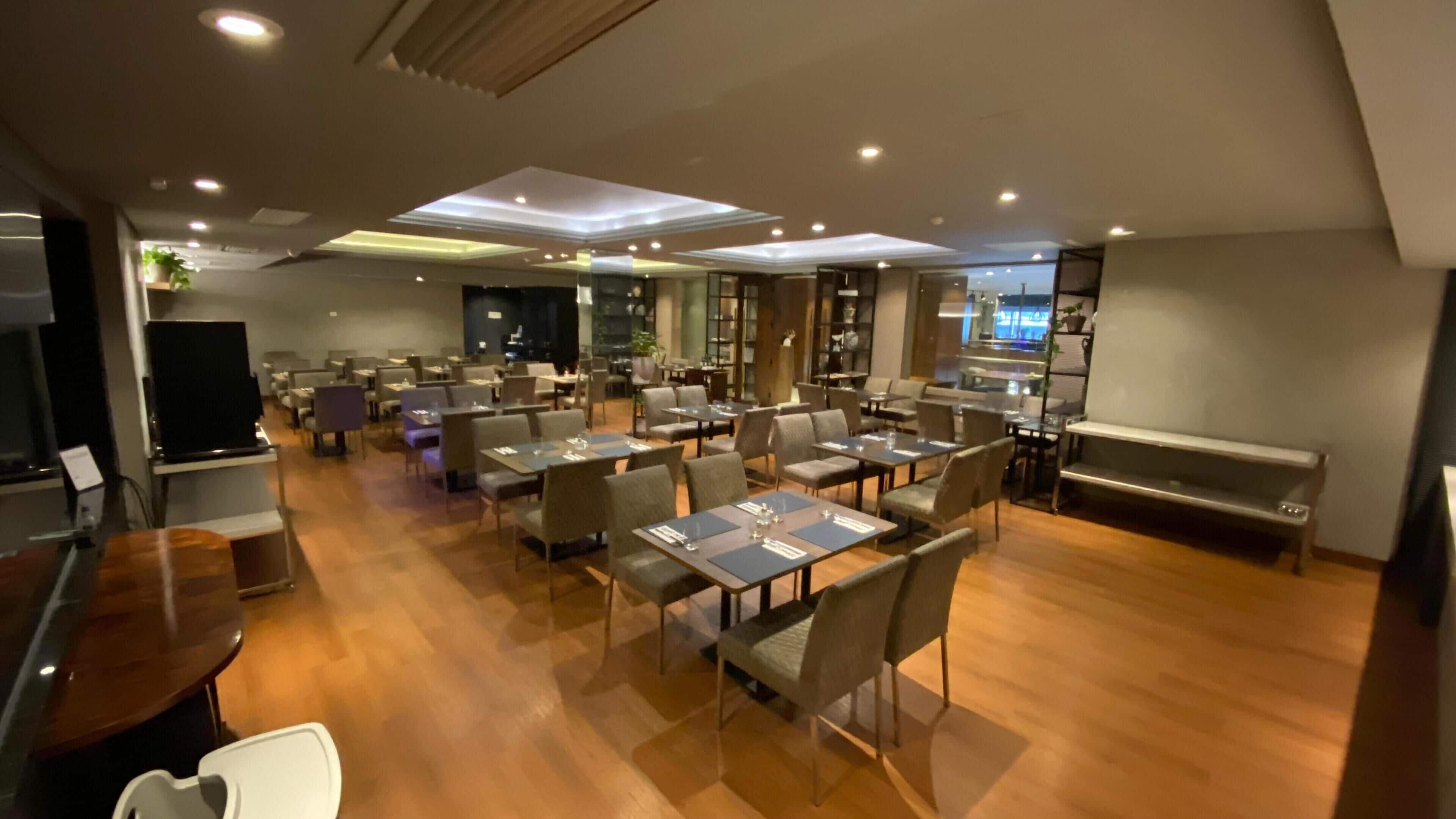 A spacious restaurant with multiple tables and chairs, a stage, and a bar area.
