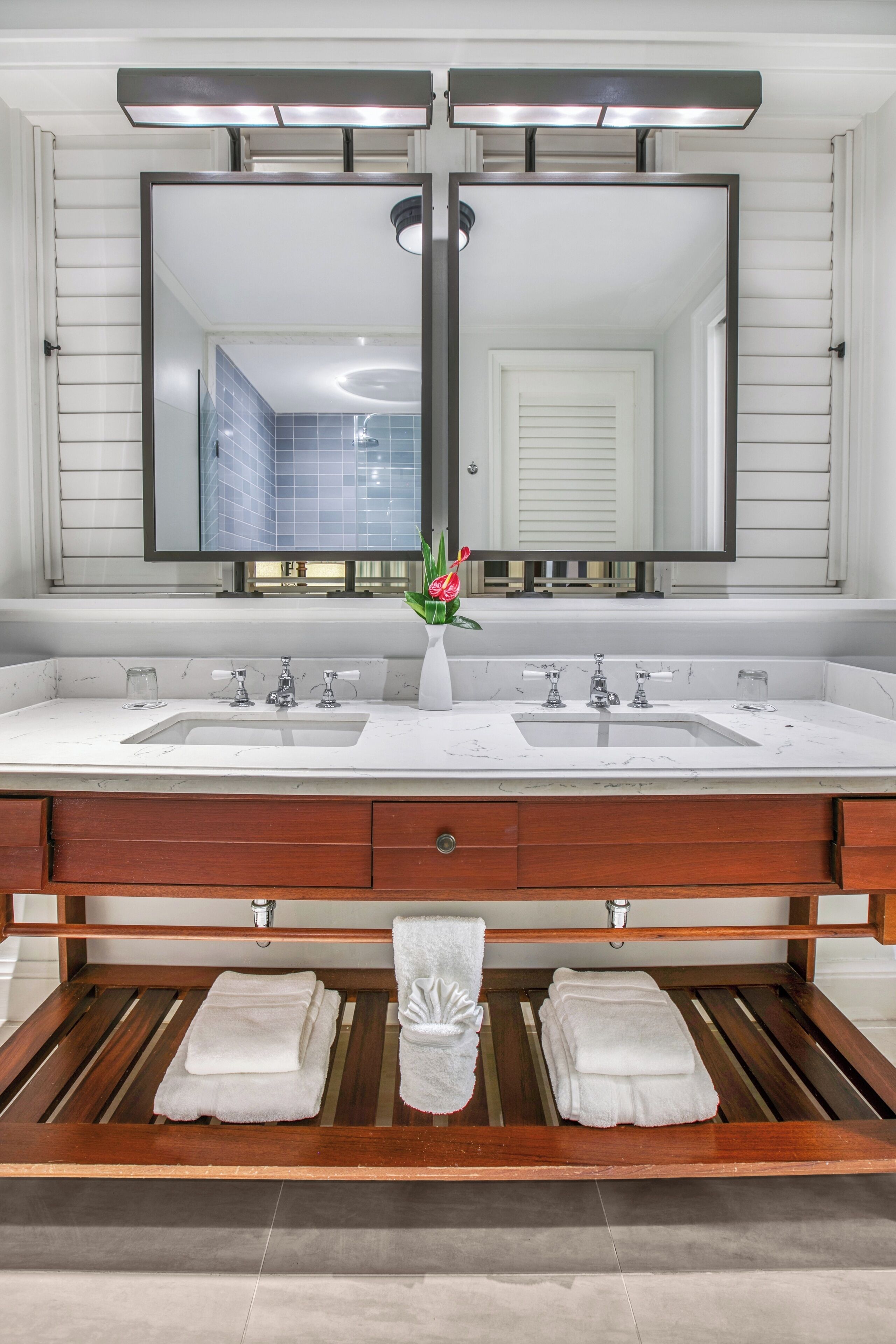 Une salle de bain avec deux lavabos, un grand miroir et un meuble-lavabo en bois.