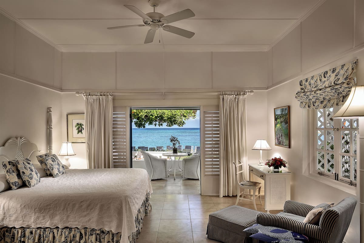 Une chambre à coucher avec un lit, une chaise, une table et une vue sur la mer.