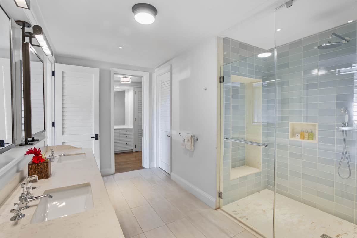 Une salle de bain moderne avec deux vasques, une cabine de douche en verre et une douche à l’italienne.