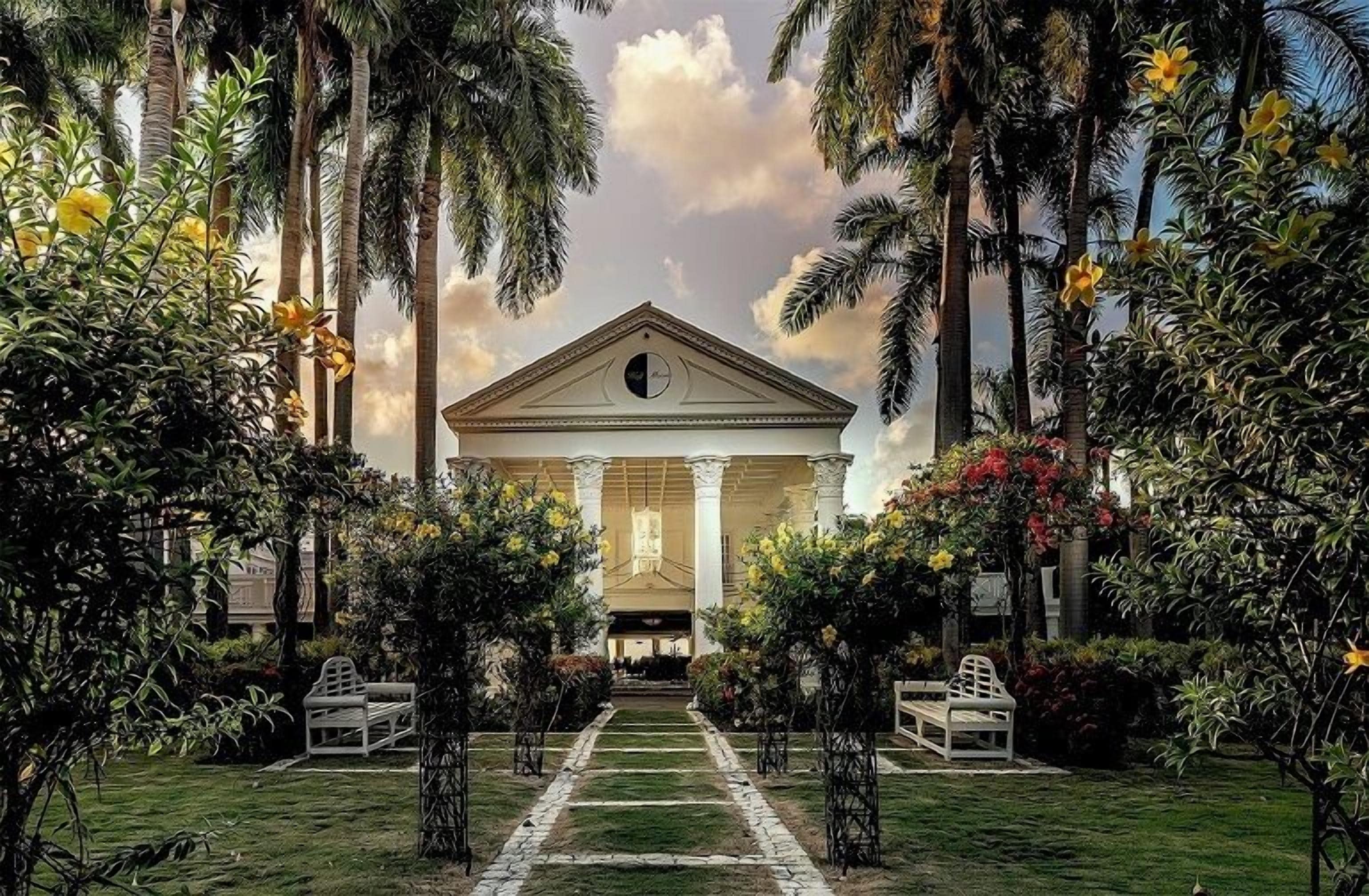A grand building with a central entrance, flanked by symmetrical pathways and lush tropical vegetation.