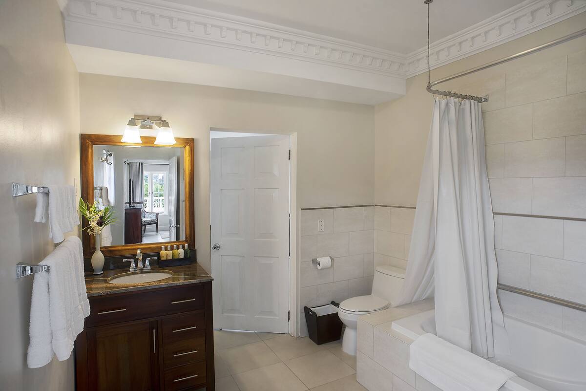 Une salle de bain équipée d’un lavabo, d’un miroir, de toilettes et d’une baignoire.
