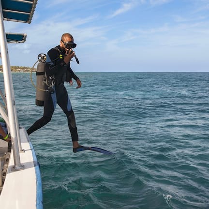 A diver in a wetsuit and fins on a boat, preparing to enter the water.