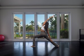 A spacious room with large windows, a red exercise ball, and a black exercise bench.