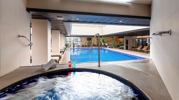 Une piscine intérieure dotée d’un jacuzzi, de chaises longues et d’une fresque murale.