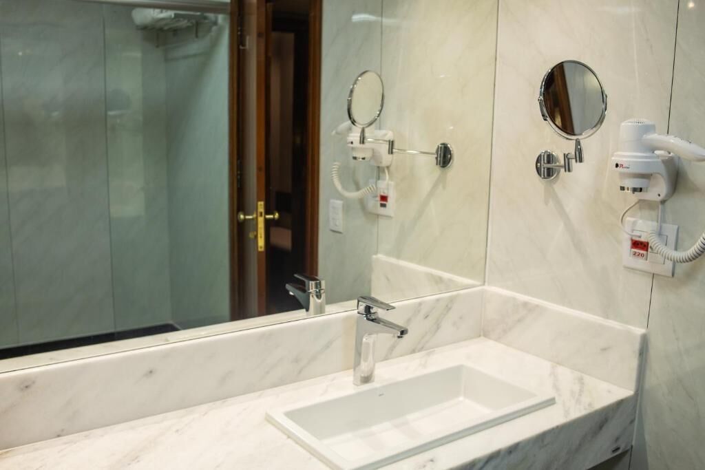 A modern bathroom with a large mirror, a handheld hair dryer, and a glass shower enclosure.