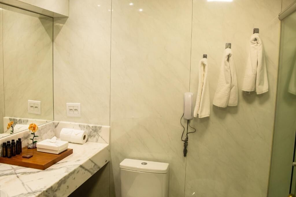 A bathroom with a marble countertop, a toilet, and towels hanging on a rack.