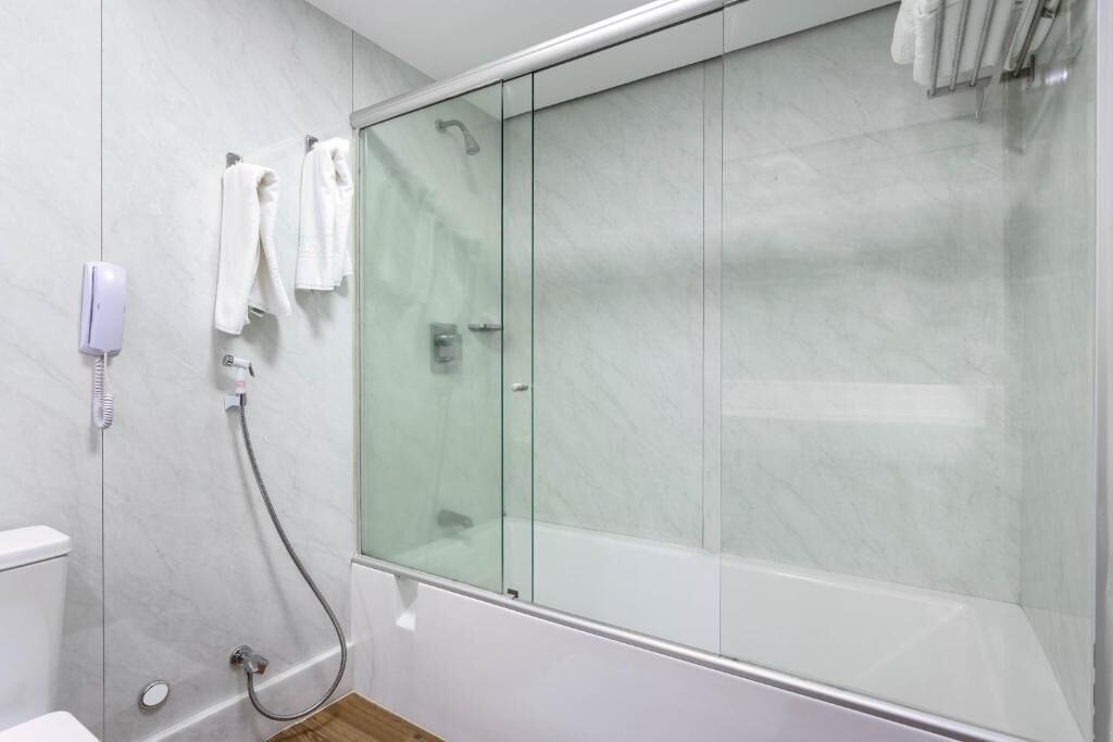 A modern bathroom with a glass-enclosed shower, a toilet, and a hand dryer.
